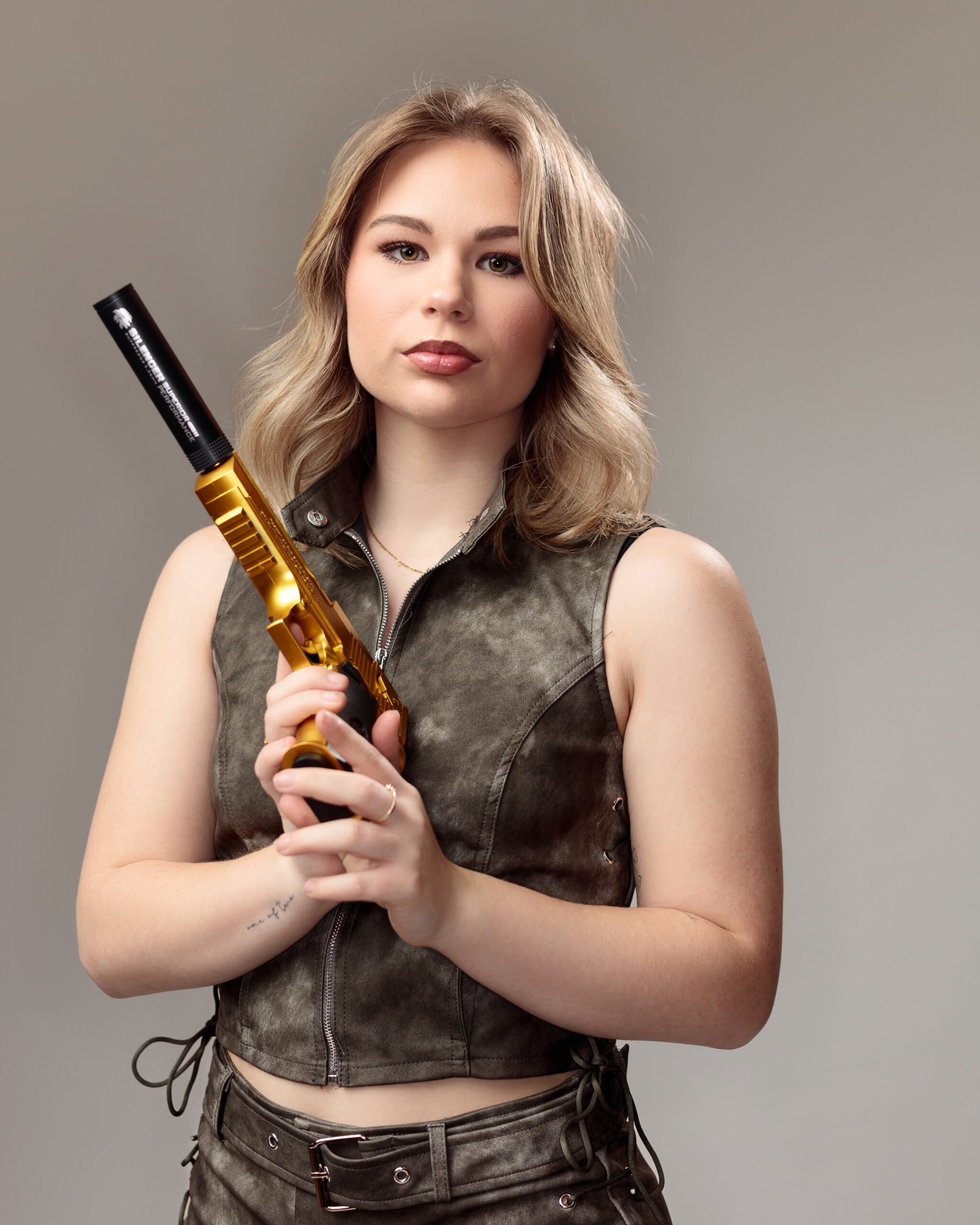 Woman holding gold gun, serious expression