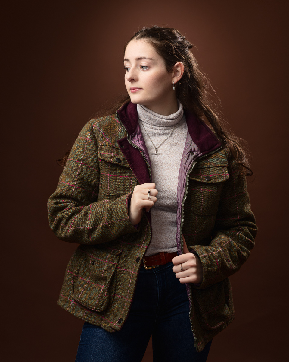 Woman in a plaid jacket and jeans looking aside.