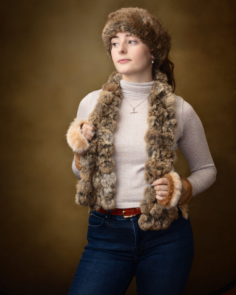 Country-style studio portrait of Sophia in a fur hat and fur scarf, looking to the side