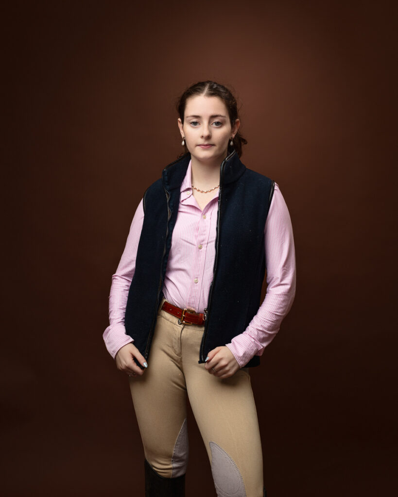 Person in equestrian outfit against brown background