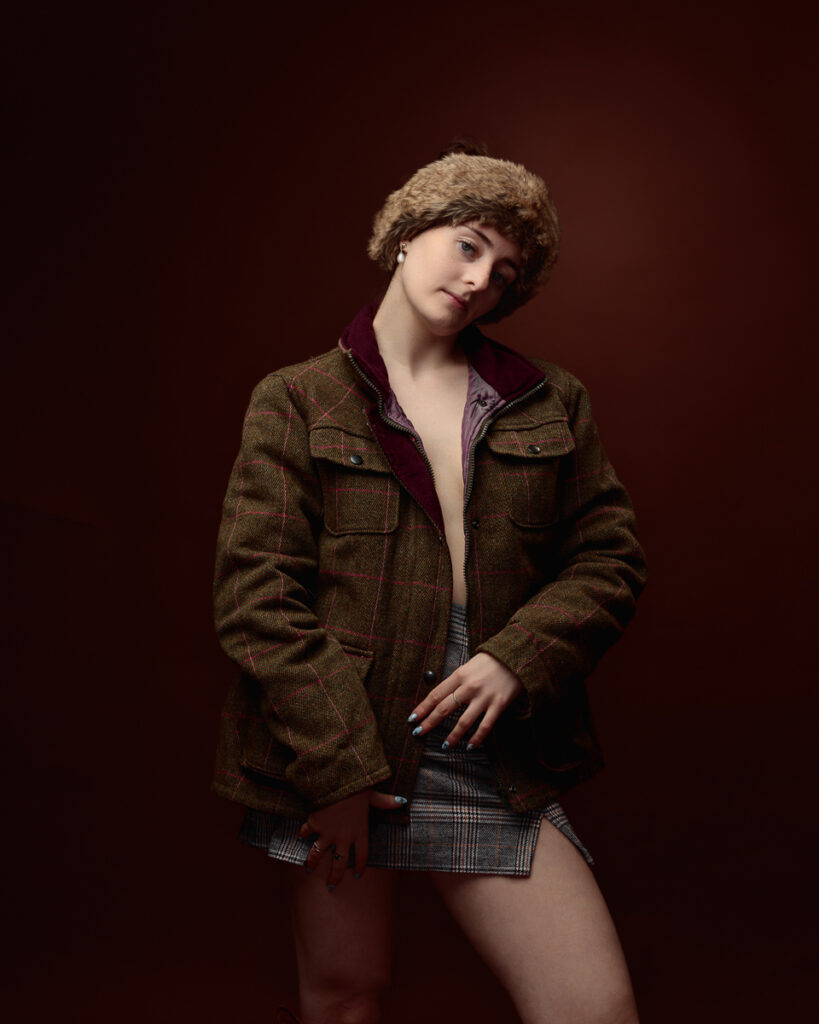 Person posing in warm clothing against brown background.