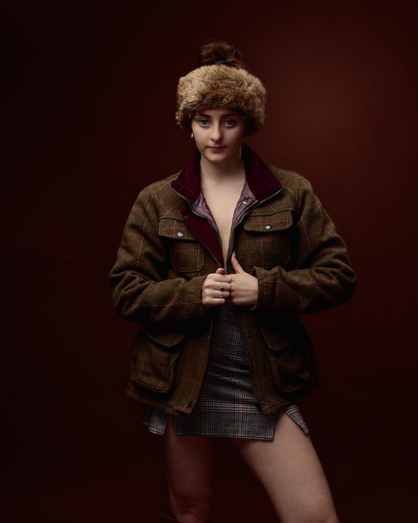 Woman in tweed jacket and fur hat posing.