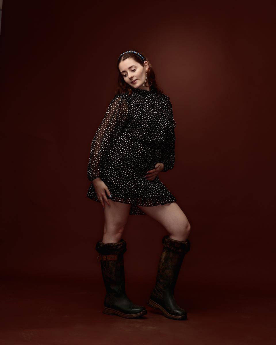 Woman in polka dot dress and boots poses.