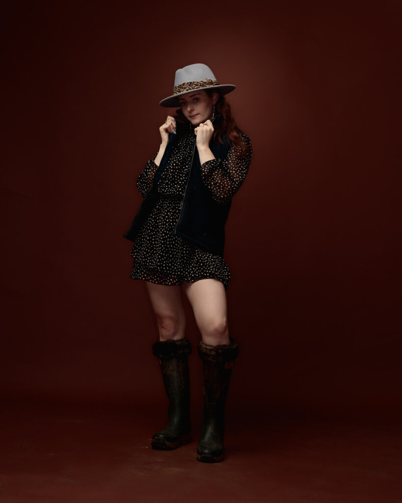 Woman in polka dot dress and boots posing.
