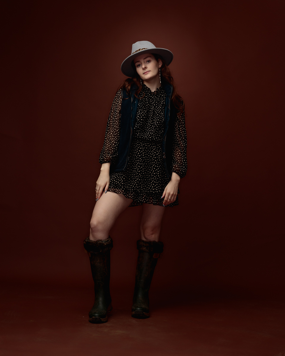 Woman in polka dot dress, hat, and boots.