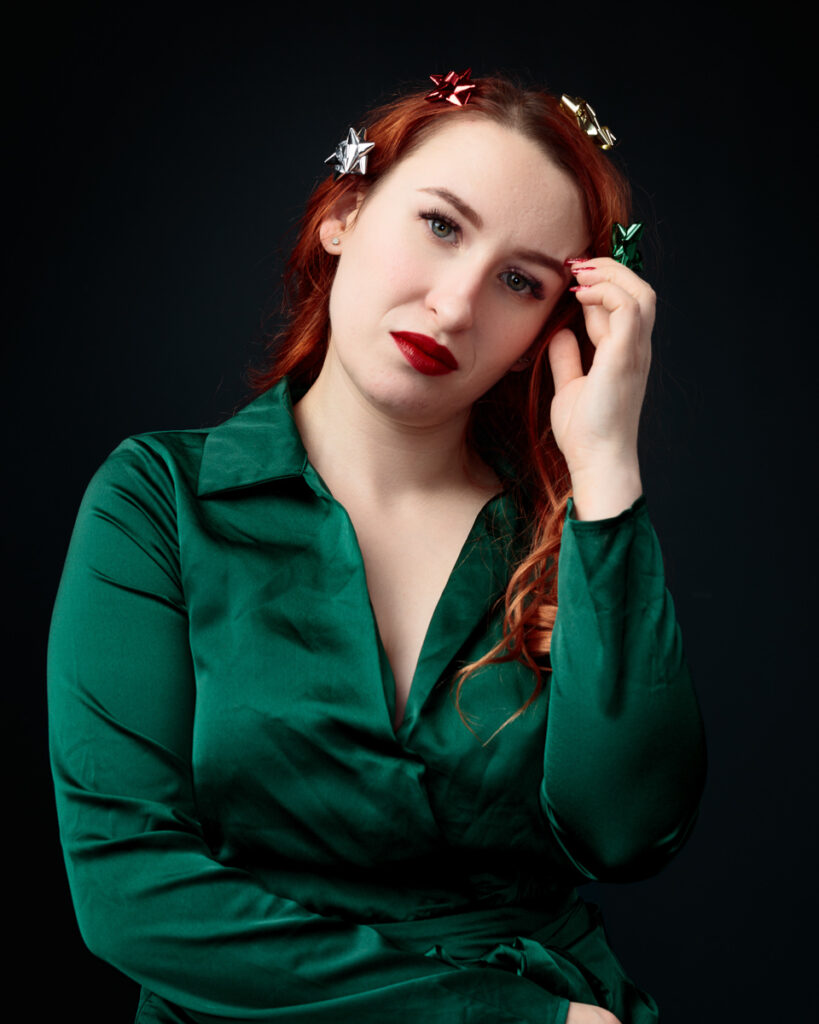 Woman with decorative bows in hair, green dress.