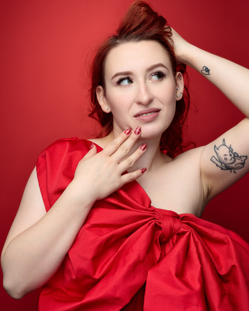 Woman in red dress, tattoos, posing thoughtfully
