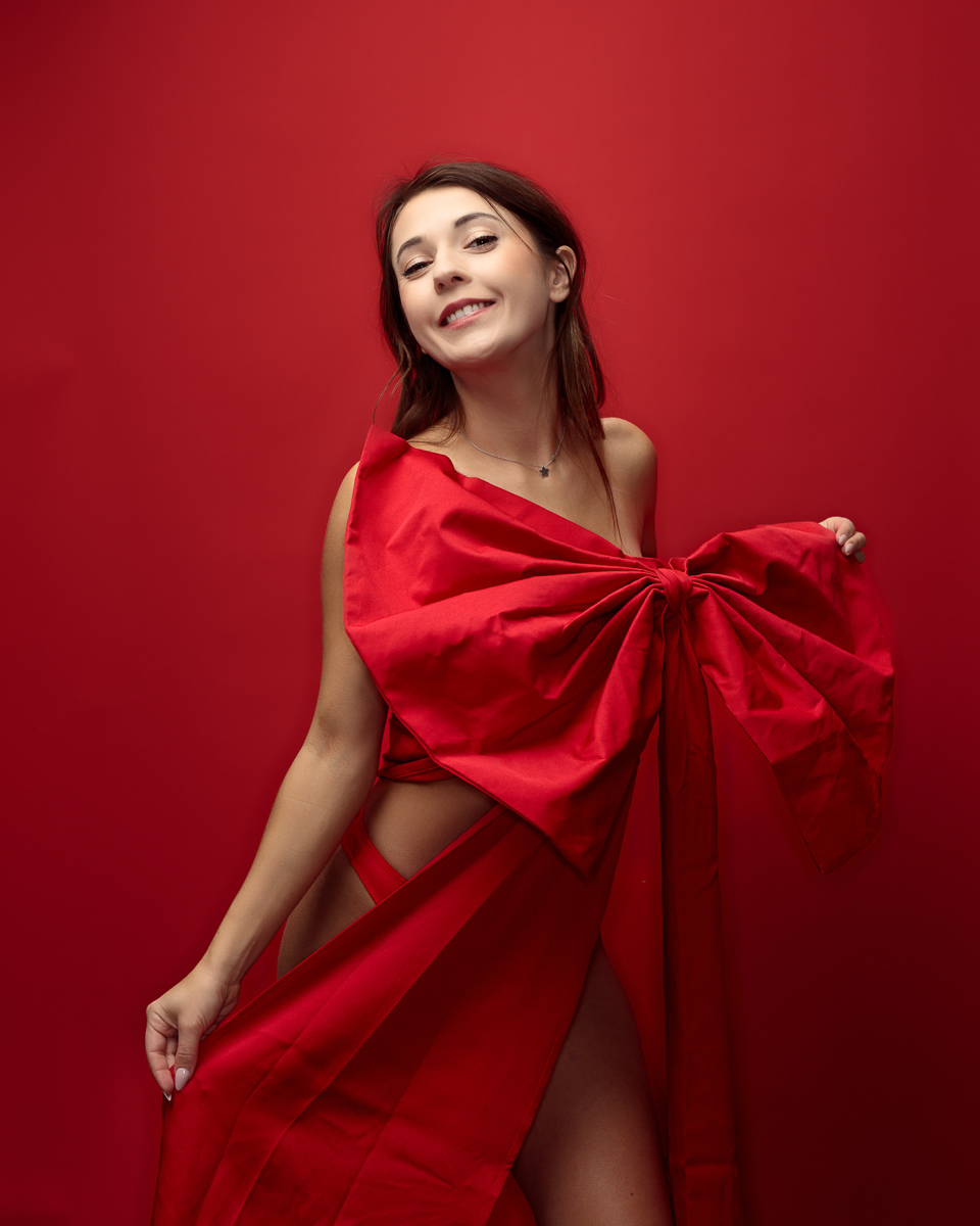 Smiling woman in a red dress against red background.