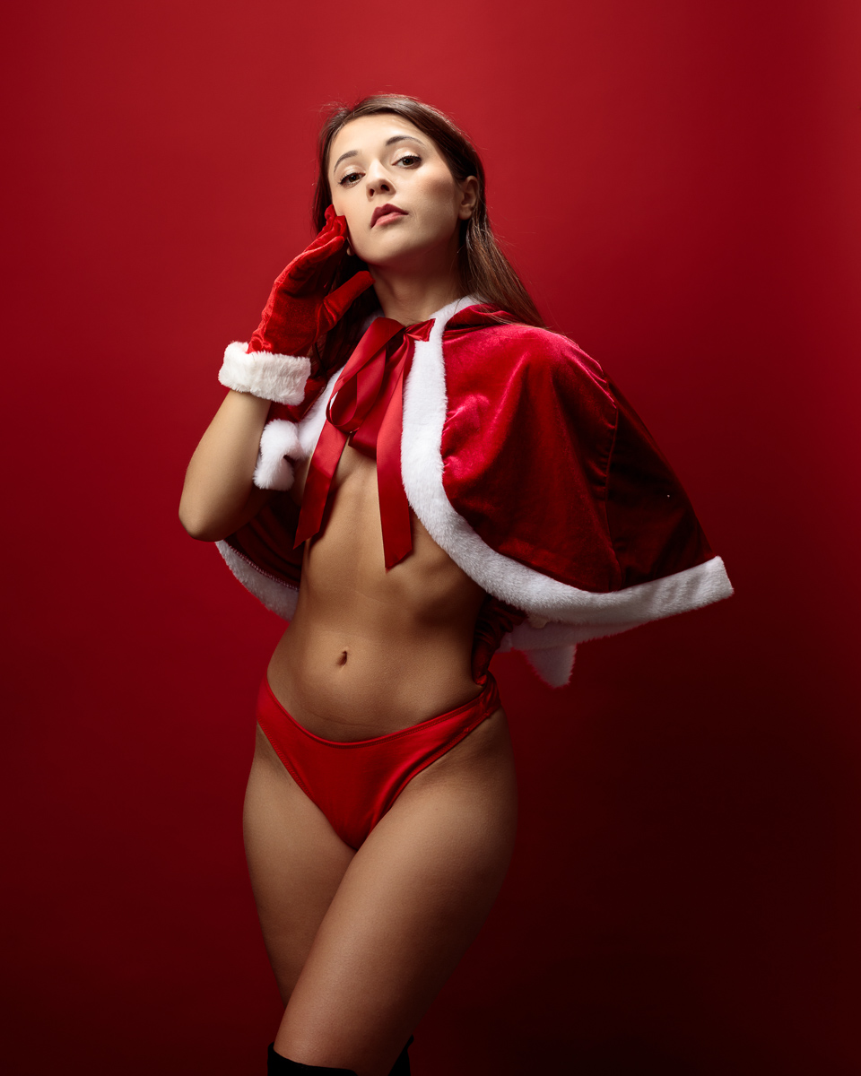 Woman in festive red outfit, red background.