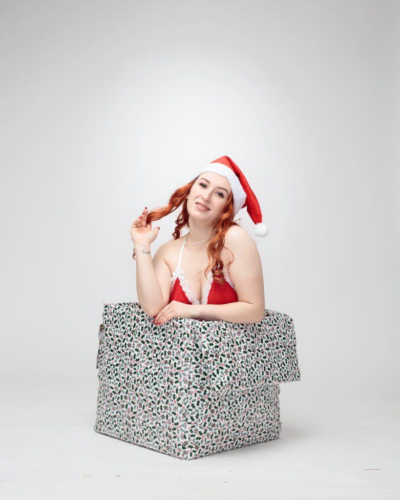Woman in Christmas outfit inside gift box.