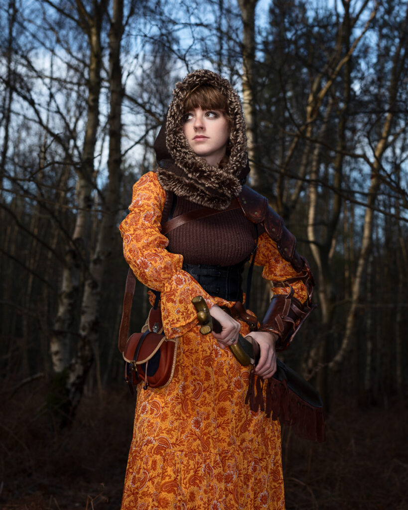 Woman in medieval costume with sword in forest