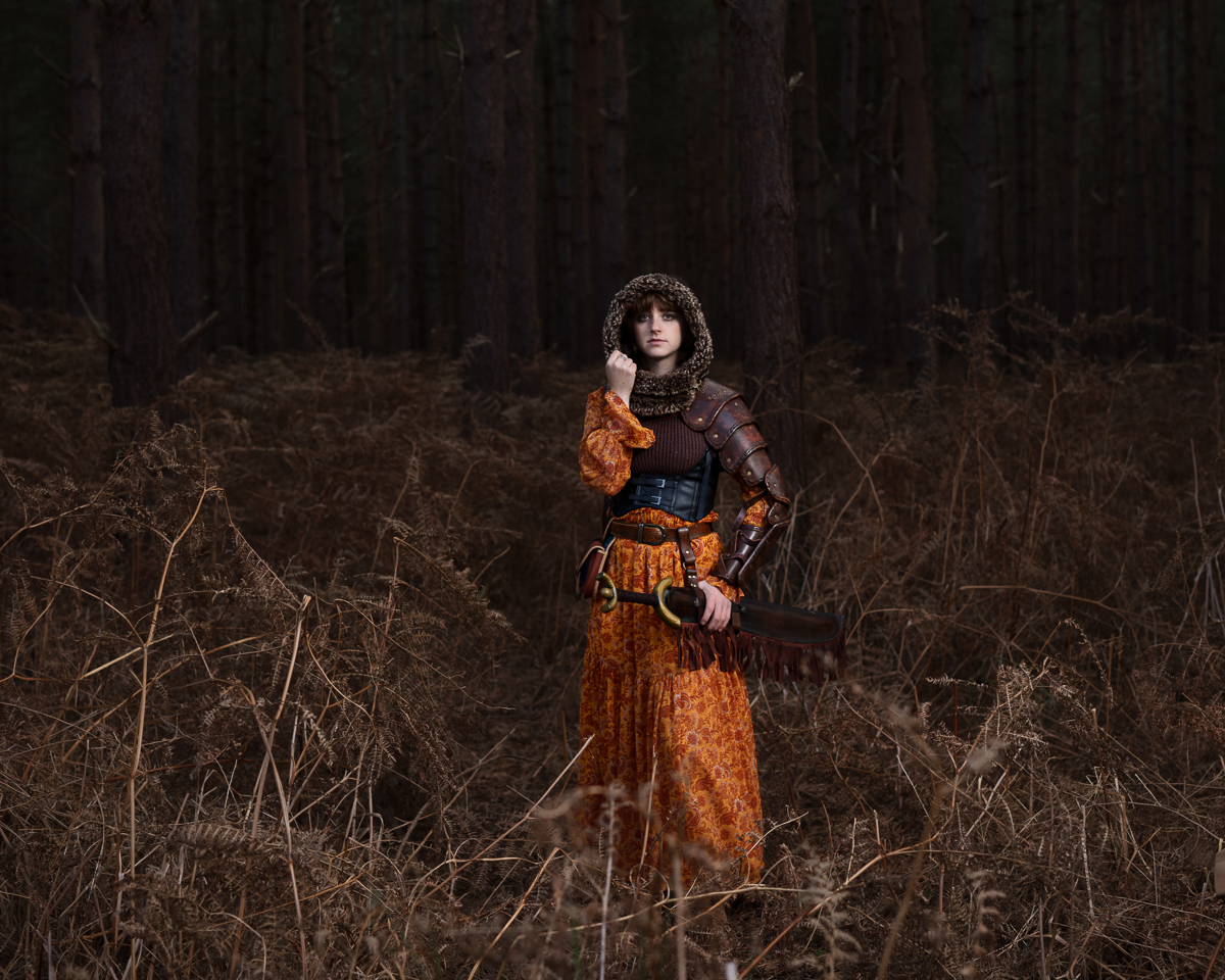 Armoured woman in forest with medieval attire.
