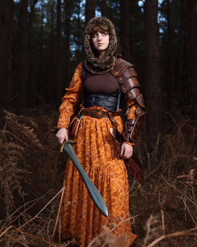 Medieval female warrior with sword in forest.