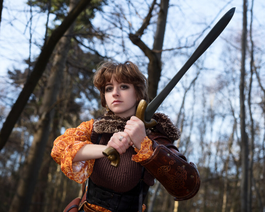 Woman with sword in forest costume.