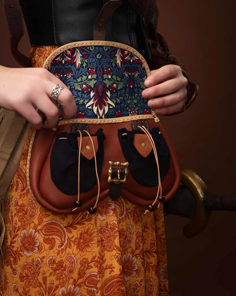 Woman holding a vintage leather purse with floral design.