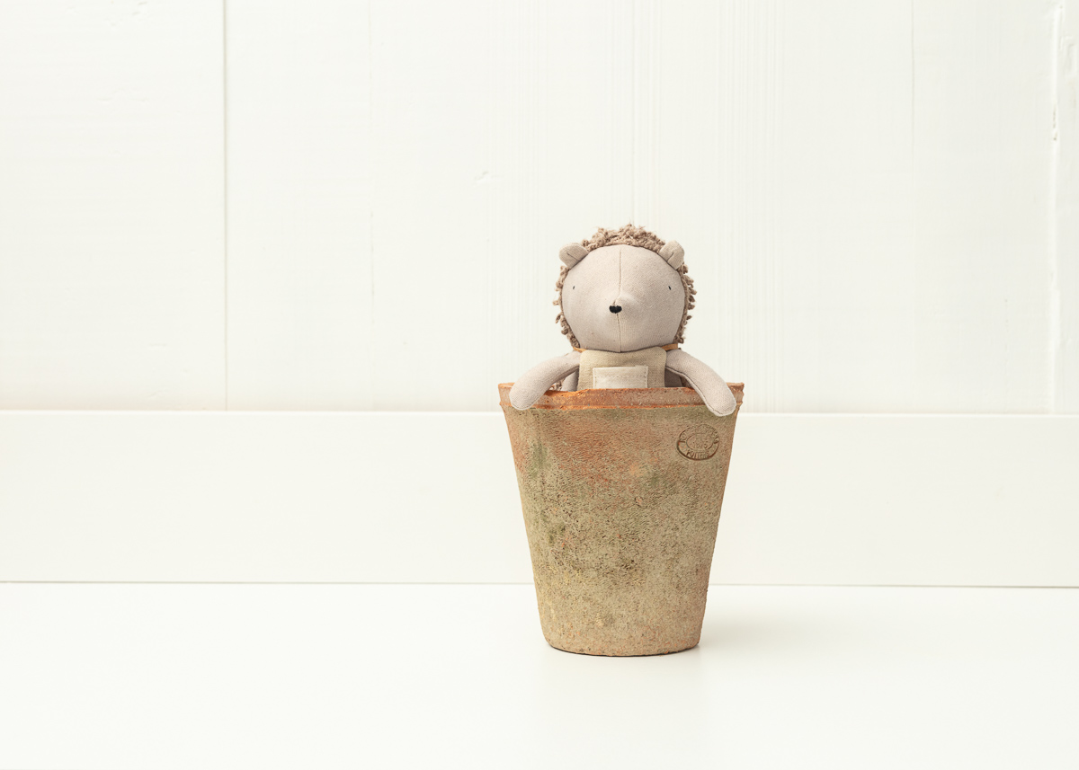 Stuffed hedgehog toy in rustic plant pot