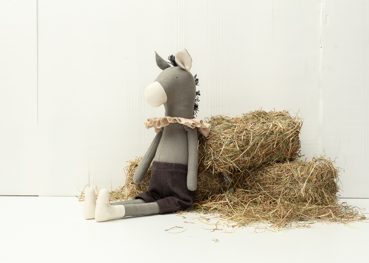 Stuffed donkey toy sitting on hay bales