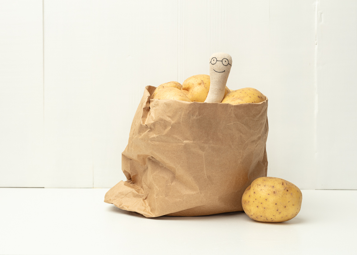 Sack of potatoes with smiling doll inside.
