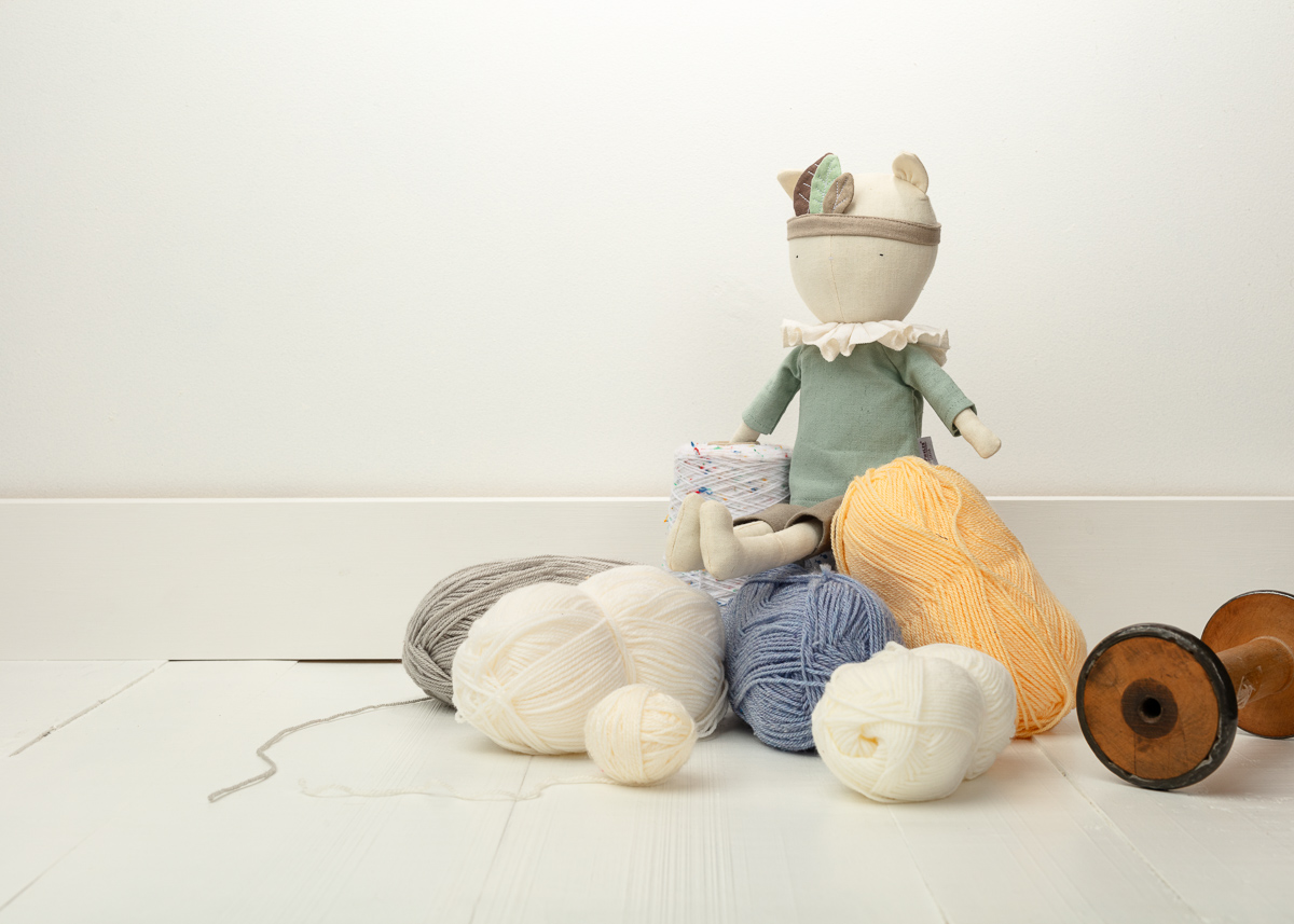 Doll and colourful yarn balls on floor