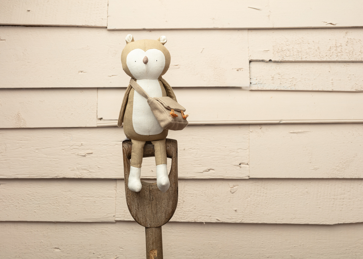 Plush owl toy on wooden stick against wall.
