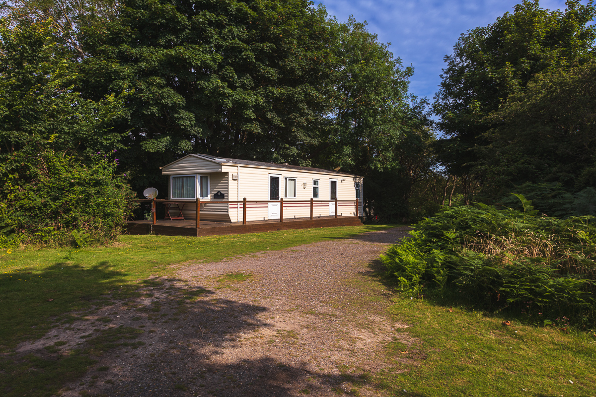 Caravan in a woodland setting with blue sky