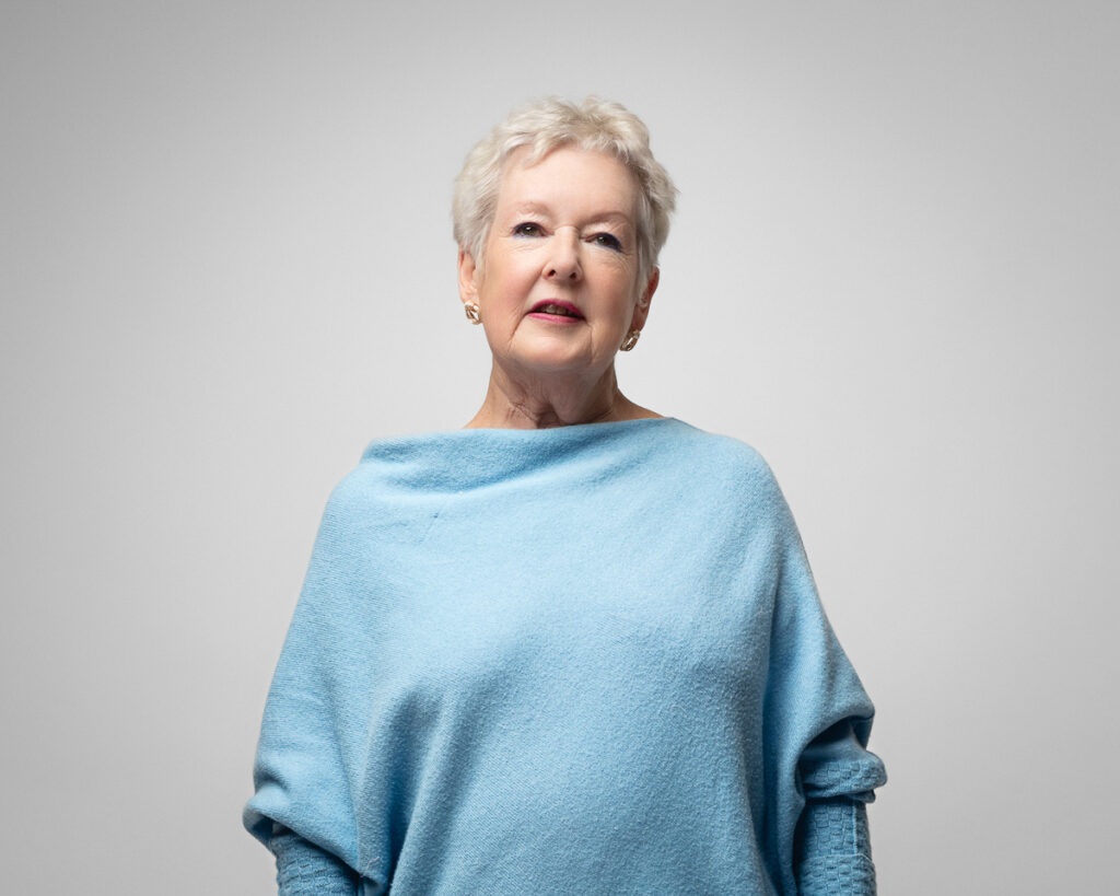 Elderly woman in blue jumper smiling.