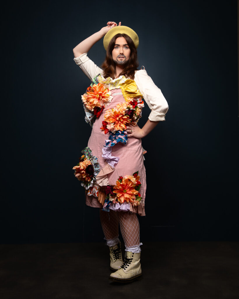 Person in floral costume posing flamboyantly indoors.