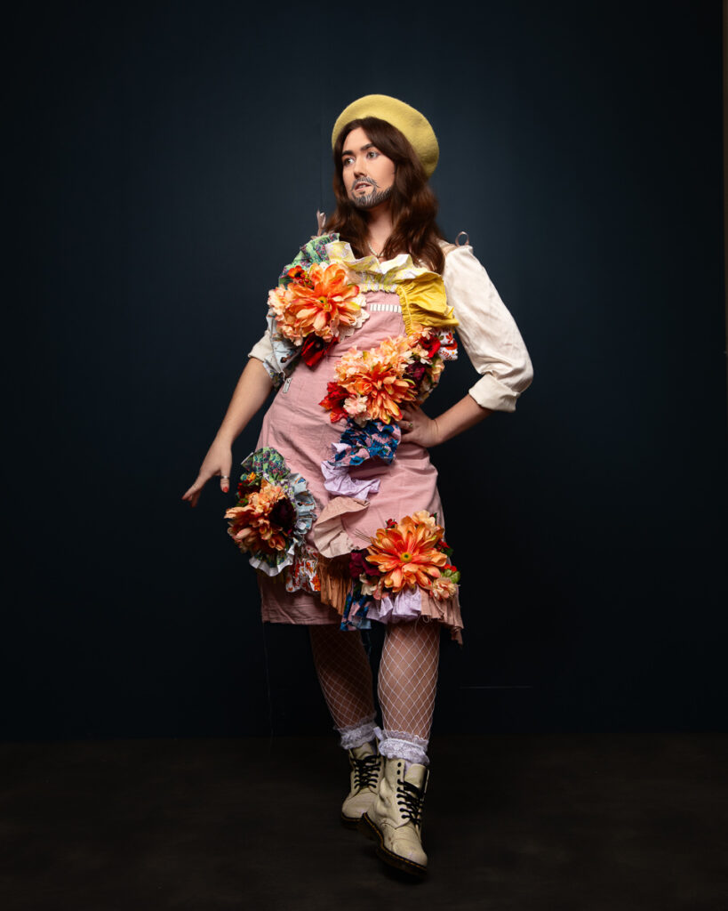 Person in floral costume and boots posing in studio.