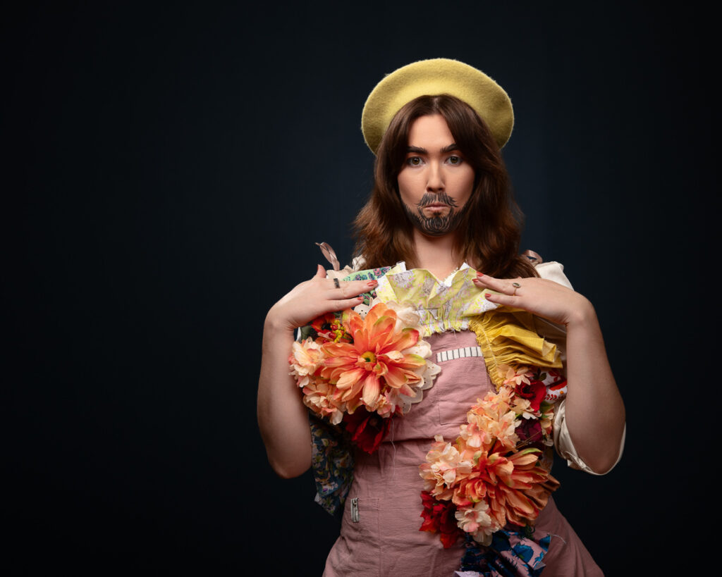 Person in floral dress with beard and beret.
