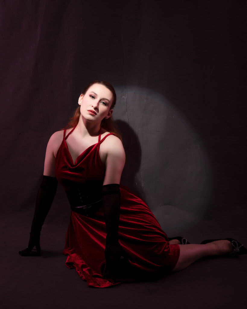 Woman in red dress kneeling on stage spotlight
