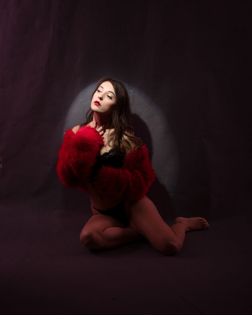 Woman posing in red fur coat on dark background.