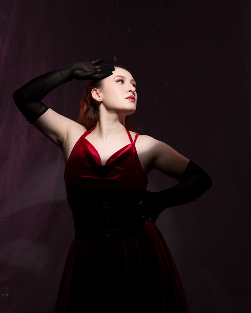 Woman in elegant red dress posing dramatically.