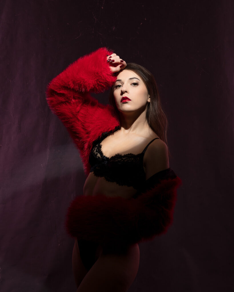 Model wearing red coat and black lingerie, posing stylishly.