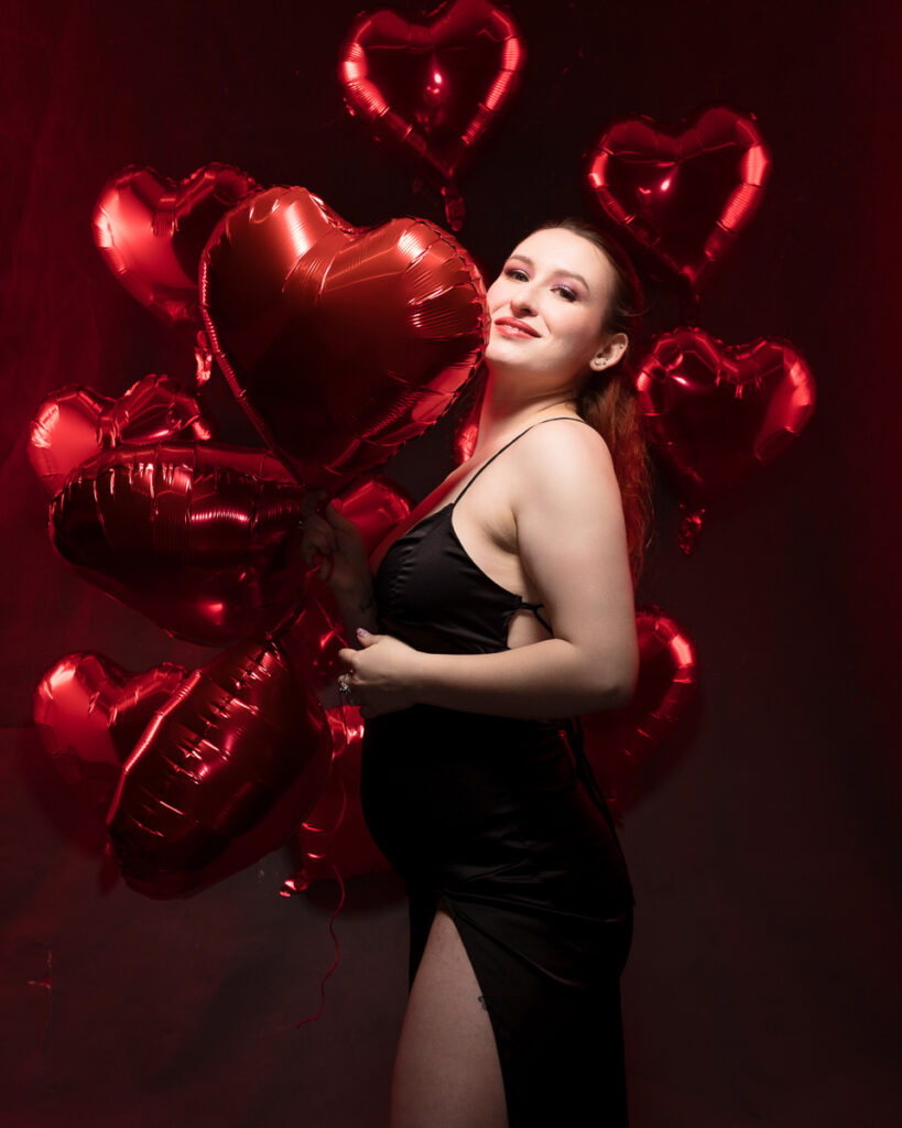 Smiling woman with red heart-shaped balloons.