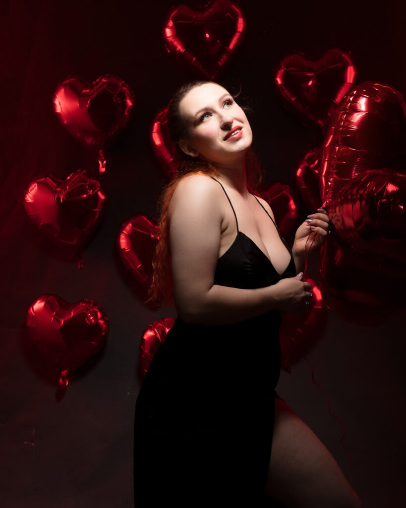 Woman holding red heart-shaped balloons