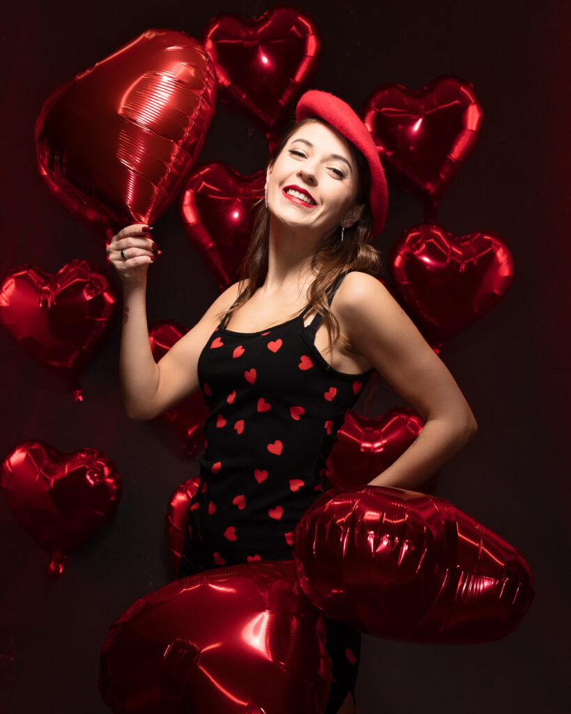 Smiling woman with red heart balloons and dress.