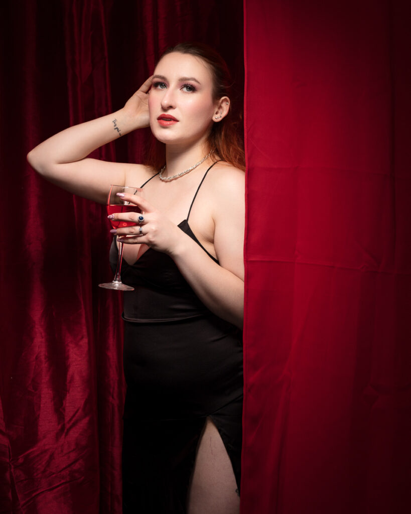 Woman in black dress holding a wine glass.