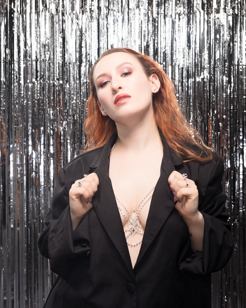 Person posing with silver backdrop, formal attire.