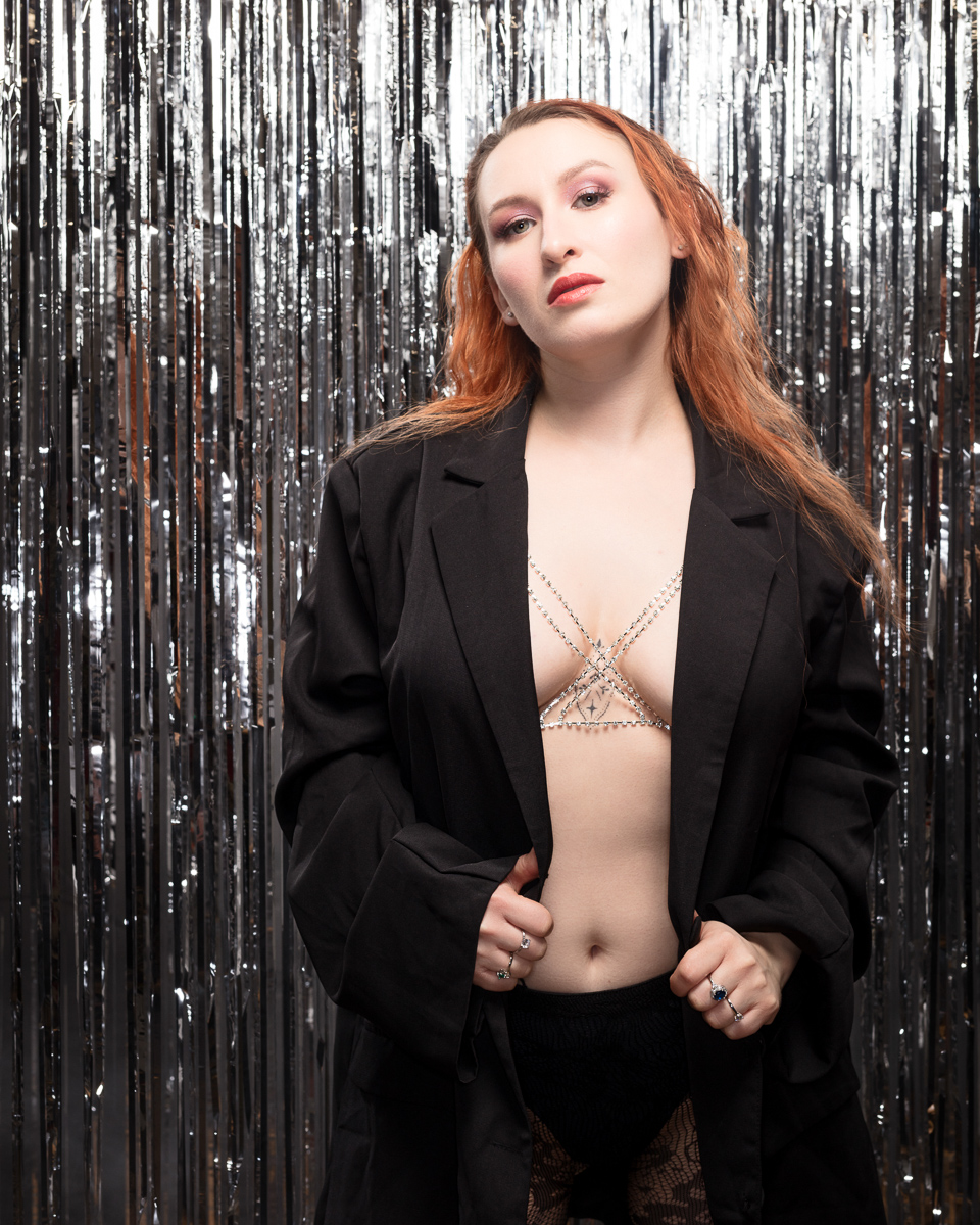Person wearing a black coat, silver background.