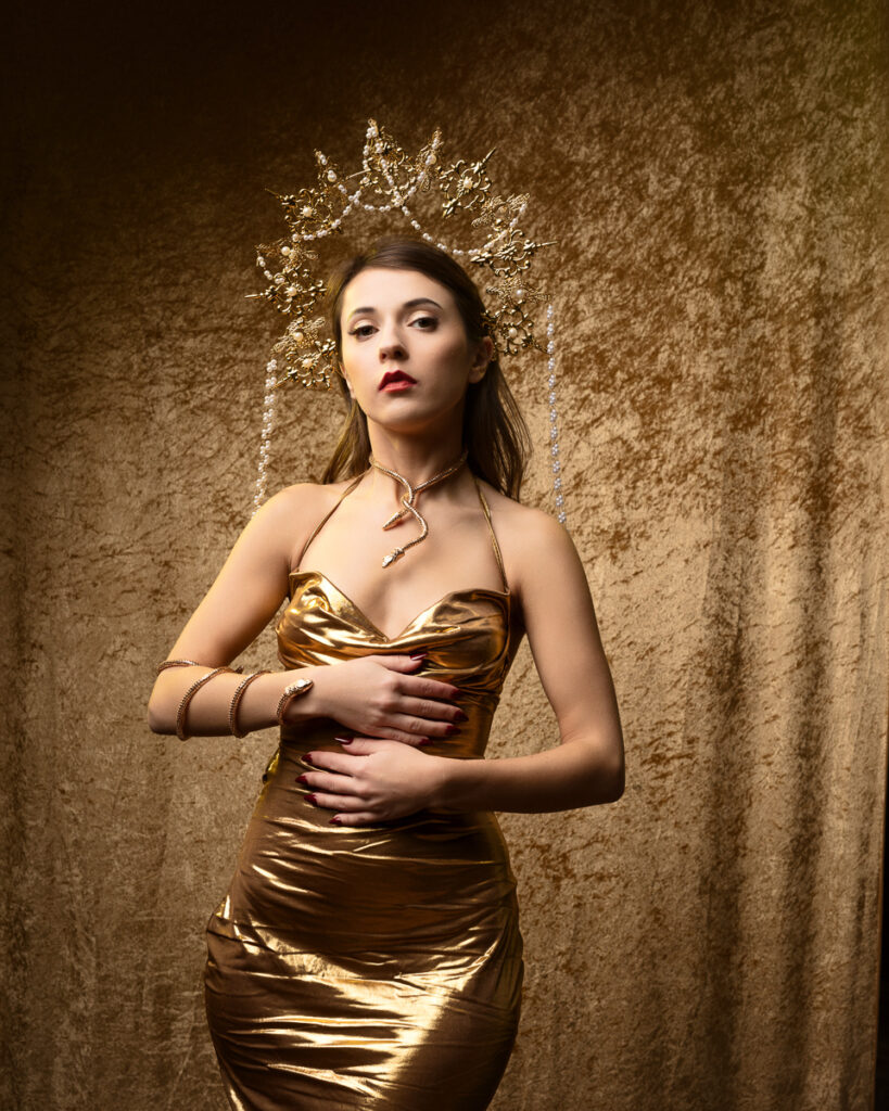 Woman in golden dress with ornate headpiece.