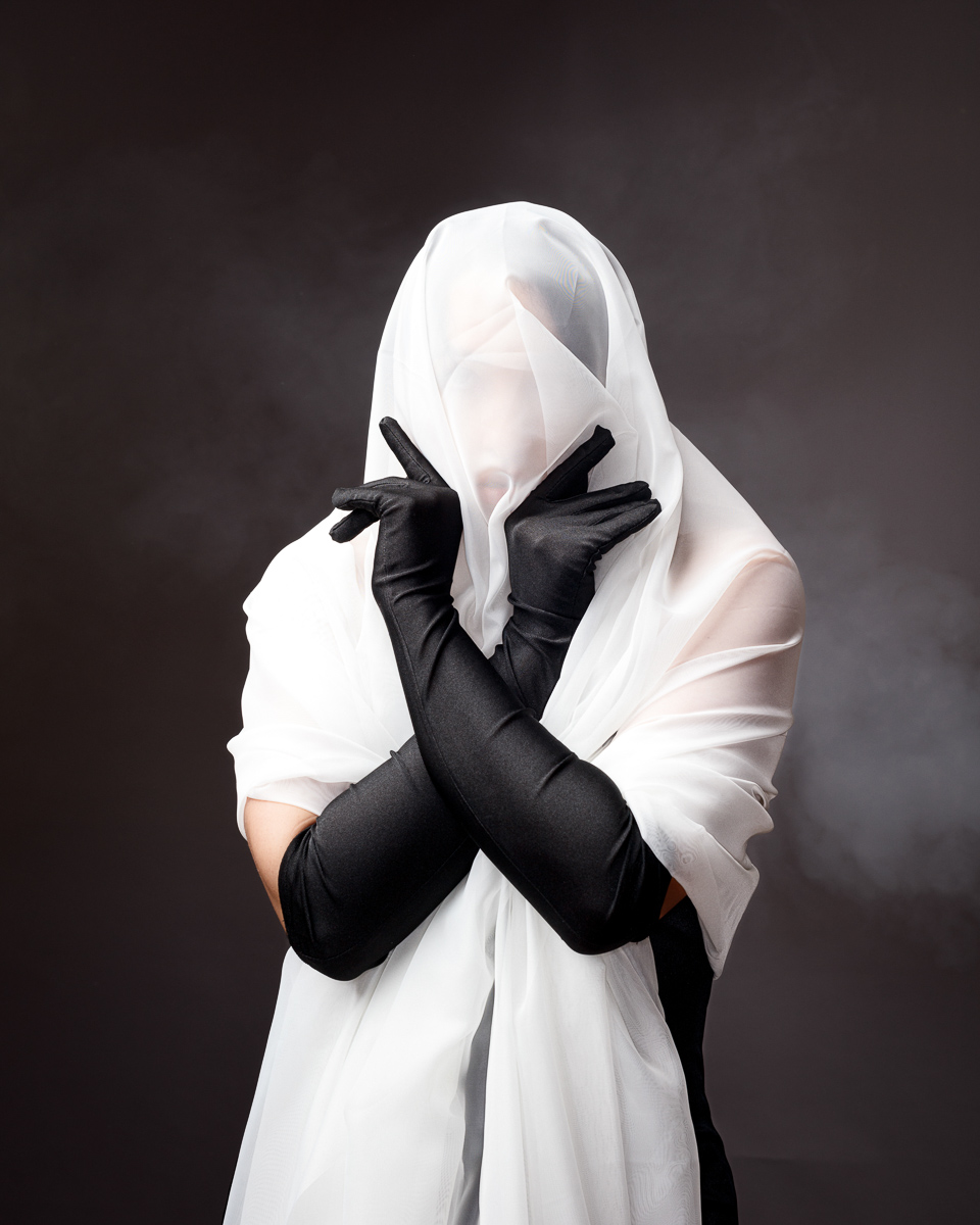 Person in veil and gloves posing dramatically.