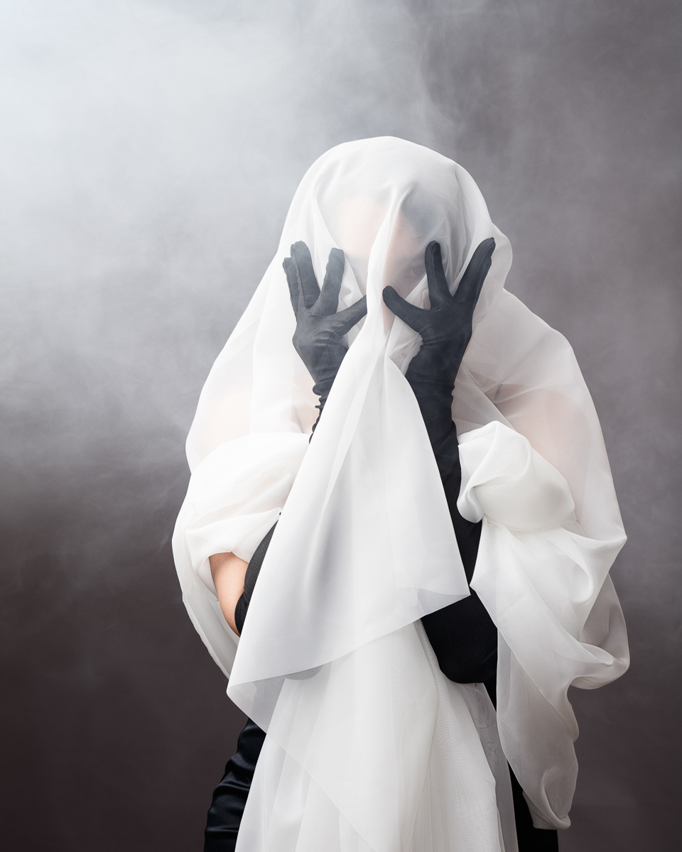Person in fog with white veil and black gloves.