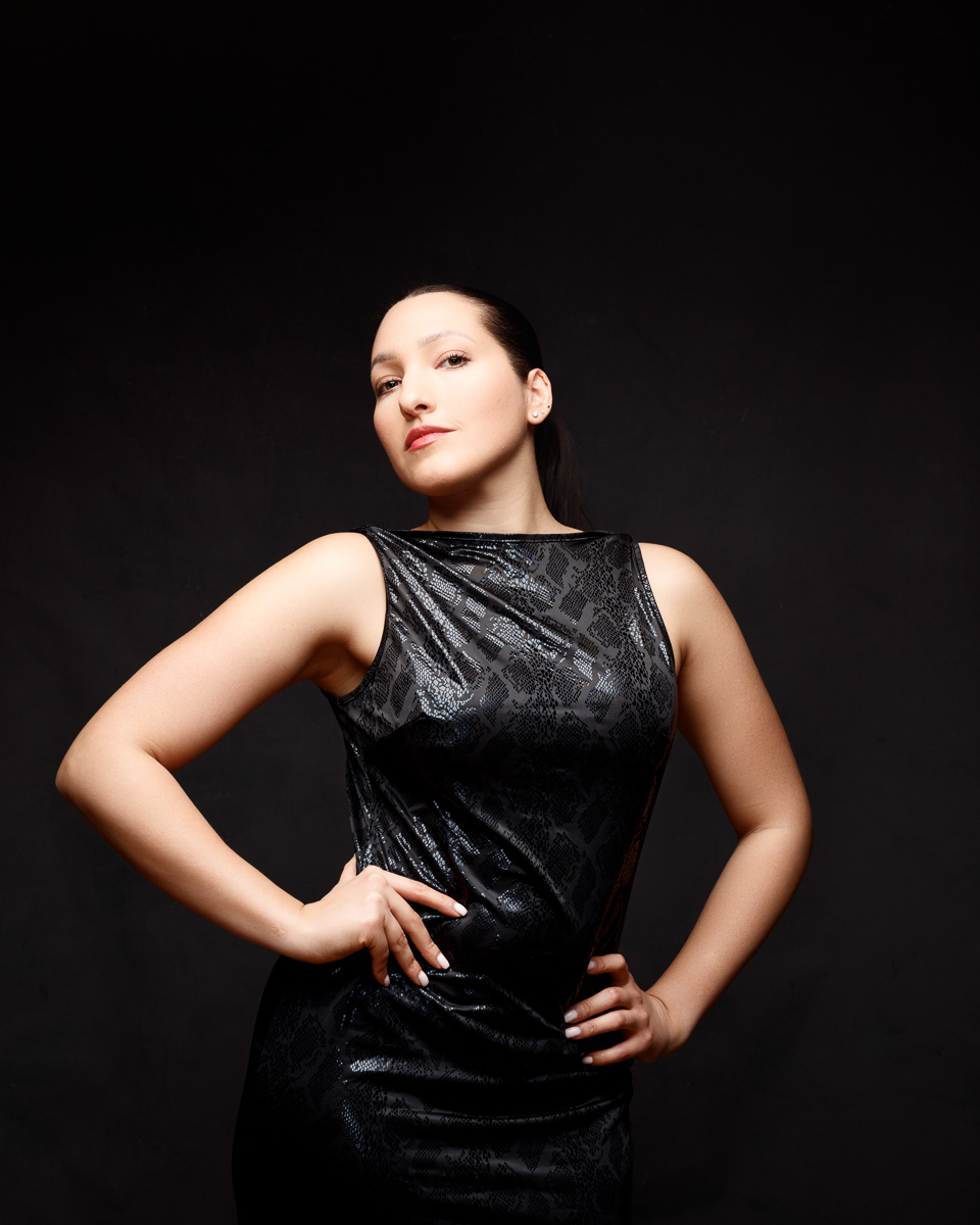 Confident woman in elegant black dress posing.