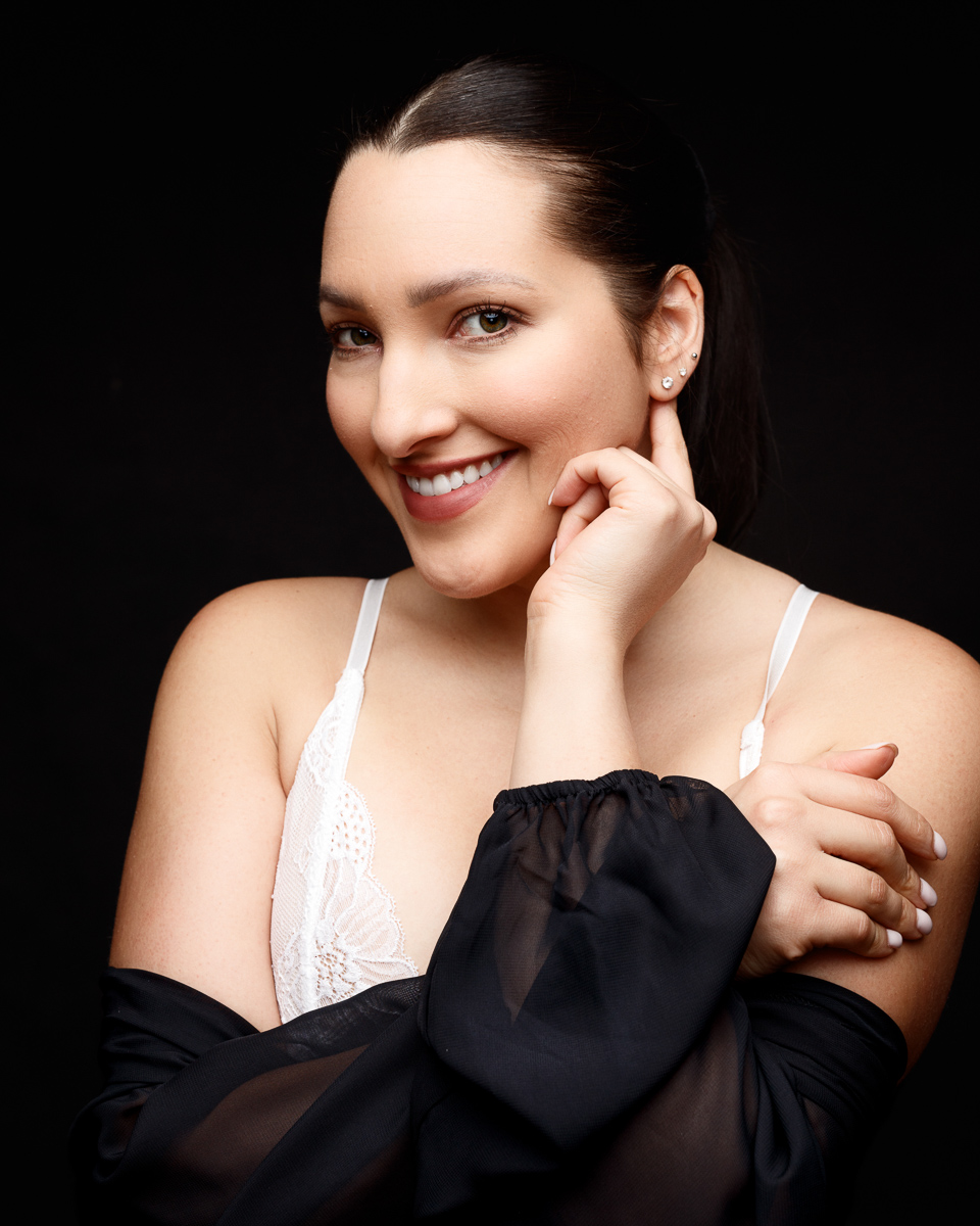 Smiling woman with black garment and white top.