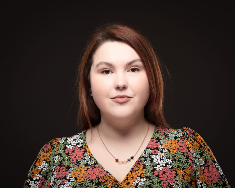 Woman in floral dress against dark background.