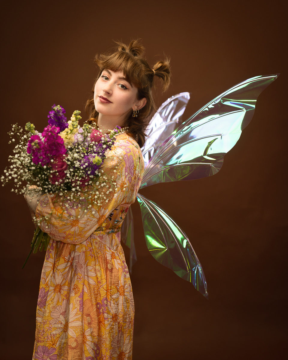 Woman with fairy wings holding flowers.