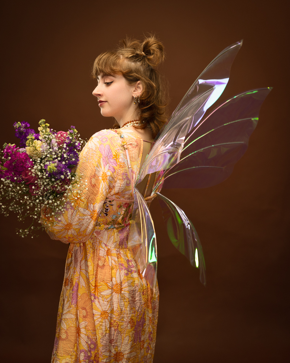 Woman in floral dress with fairy wings and flowers.