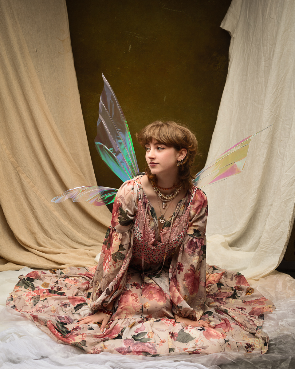 Woman in floral dress with iridescent fairy wings.