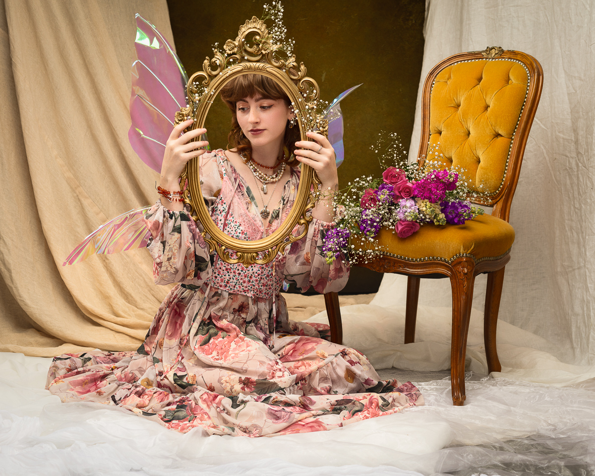Woman with wings holding ornate mirror, floral theme