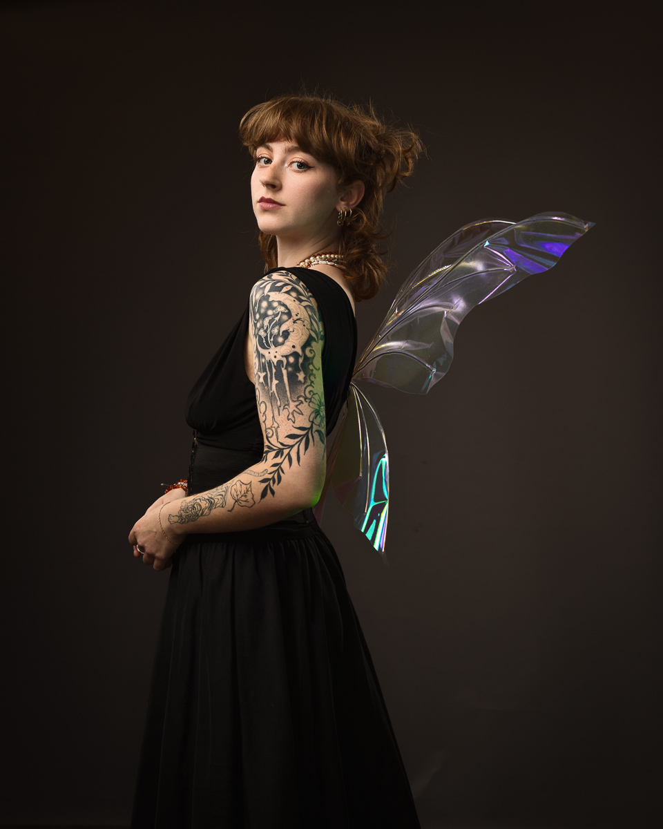 Woman with tattoos wearing fairy wings, black dress